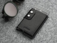 Angled front view of the black wallet with double snap closure. Six credit cards peek from the top of the wallet. 