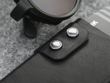 Load image into Gallery viewer, Close up to the wallet's double snap button closure. 
