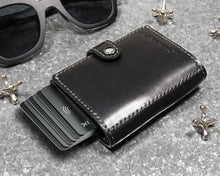 Load image into Gallery viewer, Angled front view of the black wallet with the cards slid out from the lever compartment. 

