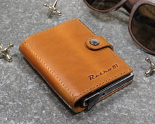 Load image into Gallery viewer, Angled front panel view of the cognac colored wallet with Retro 51 embossing. 
