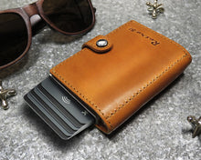 Load image into Gallery viewer, Angled view of the cognac leather card case with Retro 51 embossing. 
