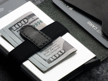 Load image into Gallery viewer, Close up to a bill folded inside the cash strap behind the aluminum case. 
