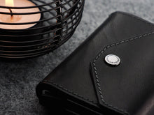 Load image into Gallery viewer, Close up to the front of the wallet. The snap closure button has the Pularys logo engraved. 
