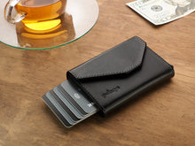 Load image into Gallery viewer, Front view of the black wallet with six credit cards peeking from the side. 
