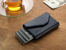 Load image into Gallery viewer, Angled view of the navy wallet with six cards peeking from the compartment. 
