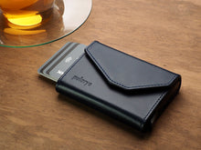 Load image into Gallery viewer, Angled view of the Navy wallet with credit cards peeking from the card case. 
