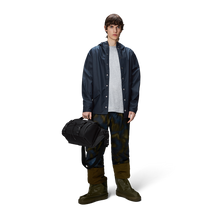 Load image into Gallery viewer, A young man wearing the navy blue rain jacket with rain boots and pants. 
