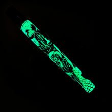 Load image into Gallery viewer, Side view of the pen on a dark background showing its glow-in-the-dark feature. 

