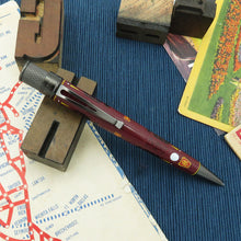 Load image into Gallery viewer, Maroon pen with silver accents on a blue textured surface with vintage items.
