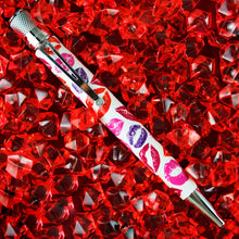 Load image into Gallery viewer, Front view of the pen placed atop a grouping of red acrylic stones.
