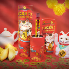 Load image into Gallery viewer, The image shows the Lucky Cat pen in its presentation gift tube. with some lucky cats, fortune cookies, and tea pot in the background.
