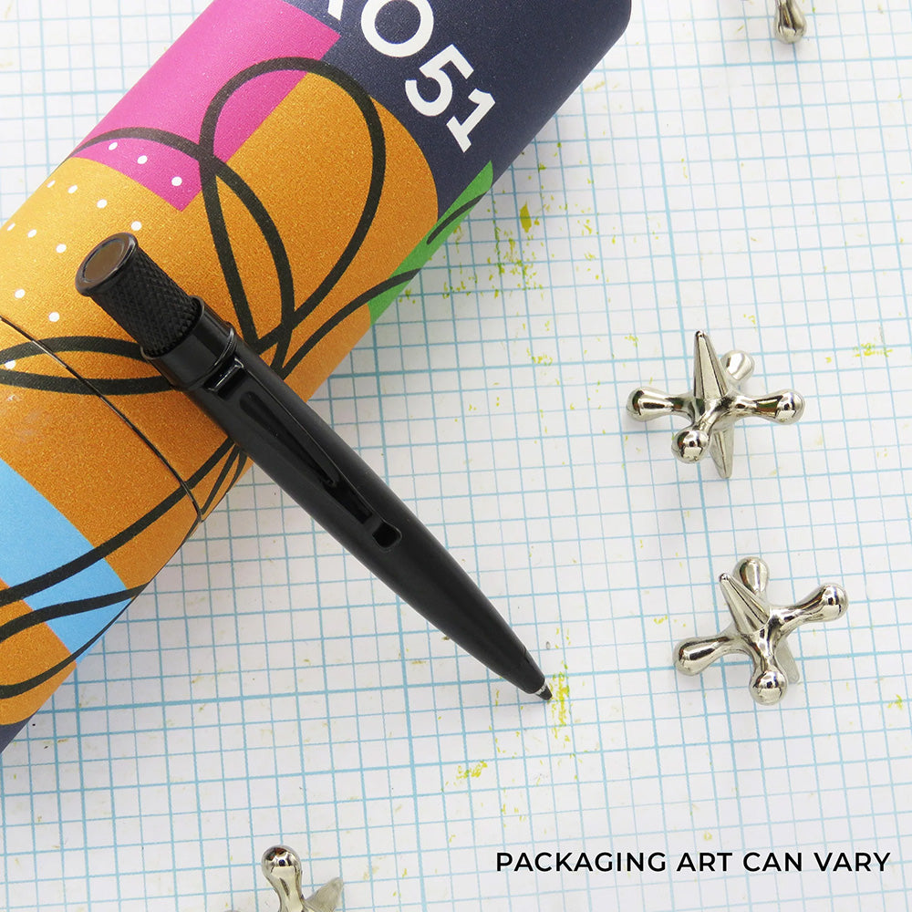Black Stealth ballpoint on a grid surface with decorative objects around it, and packaging.