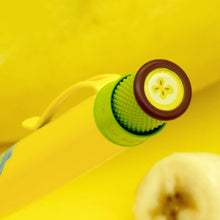 Load image into Gallery viewer, Angled close up to the top portion of the banana pen. The top trim is brown and green with a banana slice decorating the top disk. 
