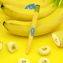 Load image into Gallery viewer, A yellow pen with a blue sticker design and a green top lies on a bright yellow surface, surrounded by whole and sliced bananas.

