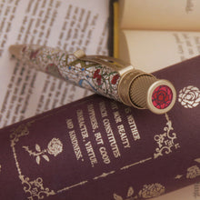 Load image into Gallery viewer, Pen with floral design top disc on a book.
