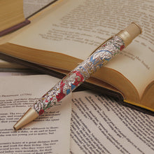 Load image into Gallery viewer, Decorative pen on an open book with floral patterns.
