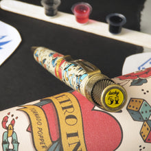 Load image into Gallery viewer, Angled view of the pen resting on the gift tube. The top disk is on focus, and has a printed design that reads &quot;Lucky 51&quot;
