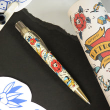 Load image into Gallery viewer, Side view of the rollerball pen arranged with a gift tube and tattoo designs. 
