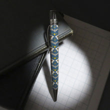 Load image into Gallery viewer, Side view of the pen with decorative background on a low-lit background.
