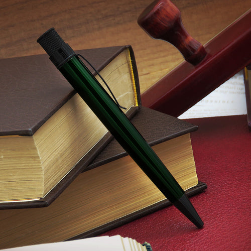 Green pen resting on a book with a wooden stamp in the background.