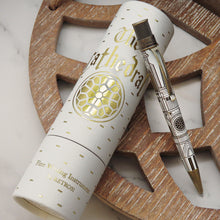 Load image into Gallery viewer, A silver and gold cathedral-themed pen with a matching cylindrical presentation tube, styled on a wooden tray over a white marble surface. The tube features gold foil details and the brand name Retro51.
