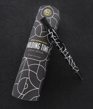 Load image into Gallery viewer, The pen rests on top of the presentation tube, in a dark background similar to the pen design.
