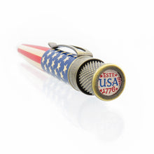 Load image into Gallery viewer, Angled view of the rollerball pen, focusing on the top disk. It has a design that reads ESTD USA 1776 with stars and stripes. 
