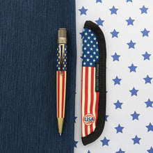 Load image into Gallery viewer, The rollerball pen and the matching Rickshaw pen sleeve arranged on a textured blue background, split by a white background with blue stars. 
