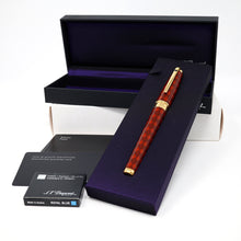 Load image into Gallery viewer, The open black presentation box containing the red with argyle design pen on a purple interior lining, with the brand name S.T. Dupont, along with the ink cartridges, and documents.
