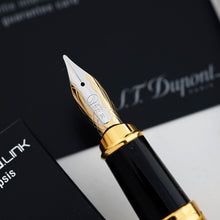 Load image into Gallery viewer, A close-up of a black and gold fountain pen nib and black grip section, shown diagonally against a dark background.
