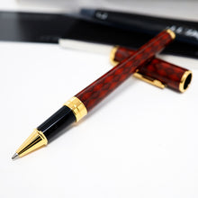 Load image into Gallery viewer, The rollerball pen with a glossy dark red and patterned barrel, accented with shiny gold trim and a black grip, displayed on a white surface with its cap in the background.
