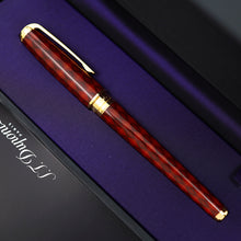 Load image into Gallery viewer, A close-up of the rollerball pen with gold accents, resting diagonally on a purple-lined presentation box.
