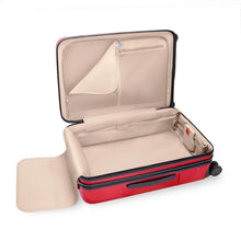 Load image into Gallery viewer, The red suitcase laid on the back panel with the main compartment opened. It features zipper-closing compartments and a panel to hold contents in the main compartment. 
