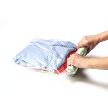 Load image into Gallery viewer, Two hands rolling the air out of a compression bag with clothes. 
