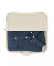 Load image into Gallery viewer, A blue shirt folded inside the packing bag. 
