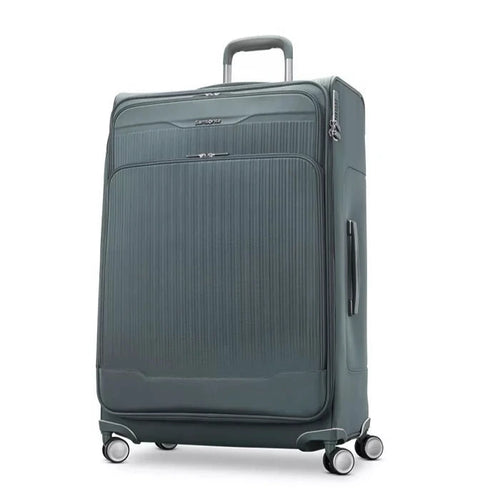 Angled front view of the slate blue suitcase with the telescopic handle partly extended. 