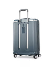 Load image into Gallery viewer, Angled back panel view of the slate blue suitcase.  It features an contact information tag. 
