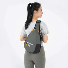 Load image into Gallery viewer, A young woman facing back while carrying the sling backpack. 
