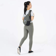 Load image into Gallery viewer, A young woman facing backwards while carrying the sling backpack. 
