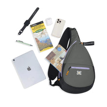 Load image into Gallery viewer, The backpack with a notebook peeking from the front pocket. A tablet, pamphlet, stationery and electronics surround it. 
