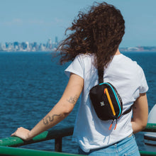 Load image into Gallery viewer, A model carrying the bag as a sling bag while looking into the ocean. 
