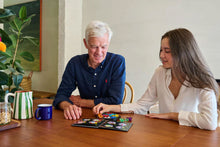 Load image into Gallery viewer, Two people playing IQ Pentagon together at a table with a cozy indoor setting.

