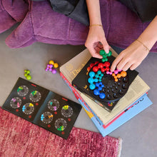 Load image into Gallery viewer, Person playing with a colorful puzzle on a book.
