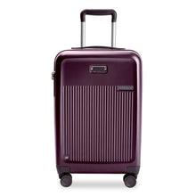 Load image into Gallery viewer, Front view of the plum-colored hard shell suitcase with the telescopic handle extended. It features a  ridged panel, a leather monogram patch, and a small Briggs and Riley logo.
