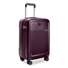 Load image into Gallery viewer, Front Angled View of the plum colored hard shell suitcase. It has a ridged front panel, a leather monogram patch, and a small Briggs and Riley logo. The telescoping handle is extended.
