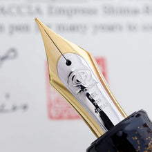 Load image into Gallery viewer, Close up to the fountain pen nib. It is two-toned, and engraved with the Taccia logo, and the text 18K 750 Japan
