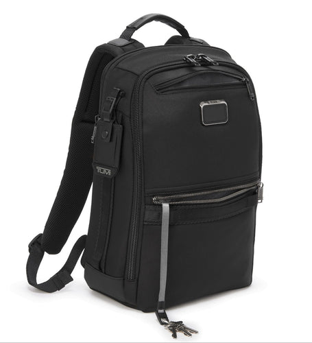 Angled front panel view of the backpack with light gray accents. The bottom front pocket interior features a cord with a clip to attach your keys. 