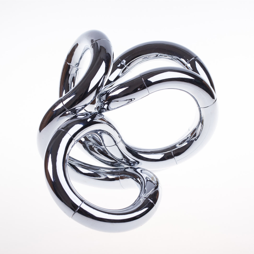 A chrome coy olored sculptural art piece with a fluid, organic design, resembling a knot or tangle.