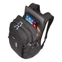 Load image into Gallery viewer, Angled top view of the black backpack with the back panel&#39;s compartment unzipped. A laptop and a tablet peek from the pockets. (Accessories not included).
