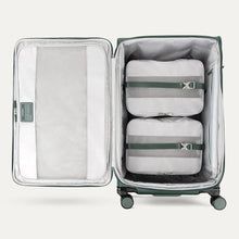 Load image into Gallery viewer, Interior view of the suitcase showing the front panel&#39;s organization pocket and the adjustable straps tied around two packing cubes. 
